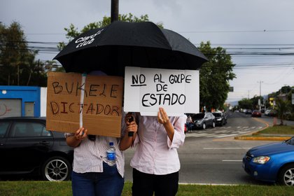 People hold signs saying "Dictator Buckily" s "Not to hit"During his protest against the sacking of the Supreme Court judges and the Attorney General by the Salvadoran Congress, in San Salvador, El Salvador, on May 2, 2021. Reuters / Jose Cabezas